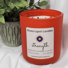 Load image into Gallery viewer, coconut soy candle with wooden wick 12 oz aura vessel- text candle name strength, white prop background, Moroccan cashmere & leather fragrance