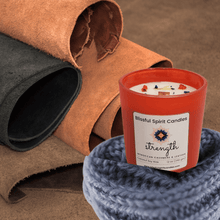 Load image into Gallery viewer, coconut soy candle with wooden wick 12 oz aura vessel- text candle name strength, white prop background, Moroccan cashmere & leather fragrance